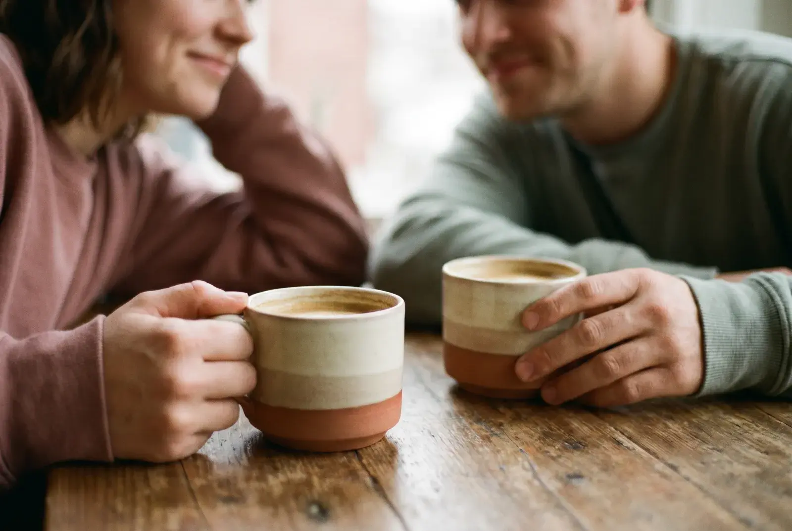 Two coffee cups between two people in a gentle conversation