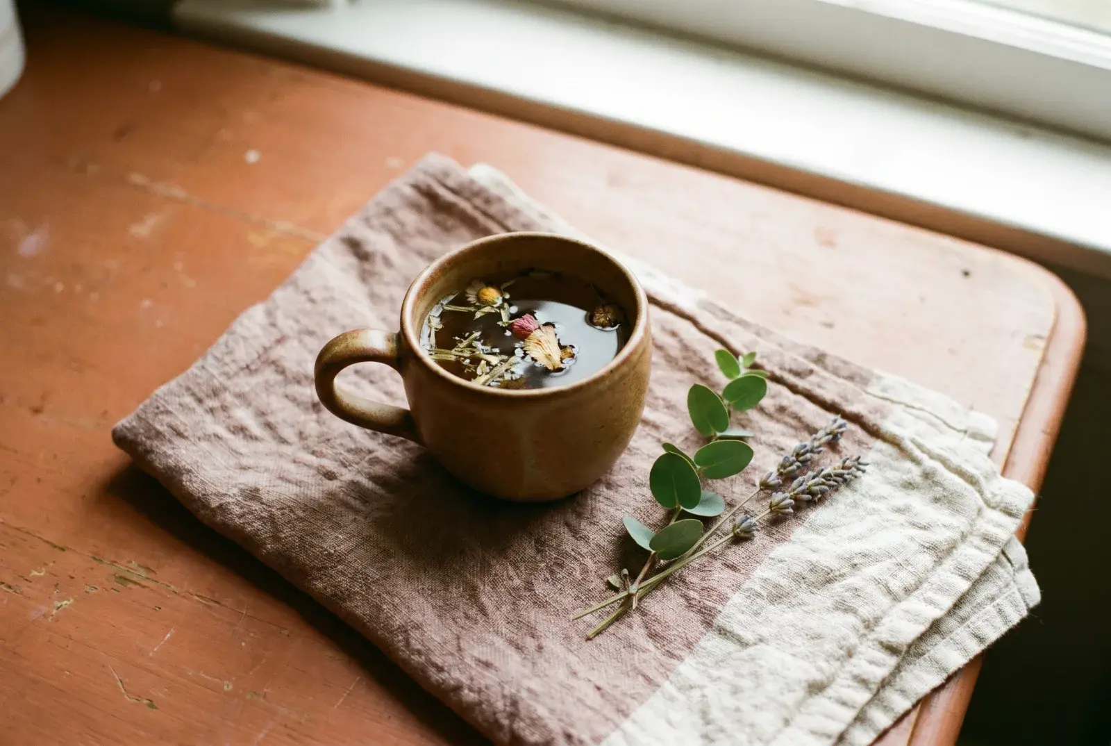 A single ceramic cup of herbal tea on linen in soft light